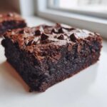 Close-up of a rich, fudgy slice of black bean brownies topped with melted chocolate chips.