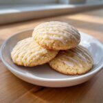 Close-up of three delicious london fog cookies stacked on a white plate, drizzled with white icing.