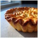 Close-up of a beautifully golden brown, flaky pie crust with decorative fluted edges, showcasing perfect texture.