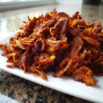 A pile of richly seasoned, shredded meat ready for homemade doner kebab, served on a white platter.
