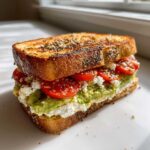Close-up of an amazing avocado tomato sandwich featuring mashed avocado, feta cheese, and sliced tomatoes on everything bagel seasoned toast.