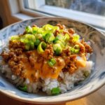 A close-up of a Bang Bang Ground Turkey Rice Bowls featuring seasoned ground turkey in a creamy sauce over white rice, topped with fresh green onions.