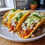 Three crispy tacos filled with spicy buffalo white bean mixture, topped with shredded lettuce, cotija cheese, and cilantro.