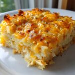 A close-up of a serving of cheesy chicken hashbrown casserole with a golden, bubbly top.