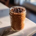 A glass jar filled with rich chocolate overnight oats, topped generously with dark chocolate chips.