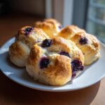 Close-up of freshly baked cottage cheese blueberry cloud bread rounds served on a white plate.