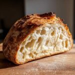 Close-up of the open crumb structure of a country loaf with sourdough discard, showing an open, airy interior and dark crust.