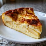 A close-up of a single slice of creamy apple custard impossible pie with a golden-brown, caramelized top.