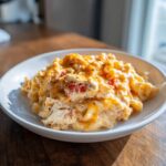 A close-up of creamy rotel pasta mixed with shredded chicken and melted cheddar cheese in a white bowl.