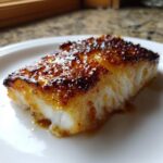Close-up of a flaky fillet of honey baked cod with a dark, caramelized, glossy glaze on top.