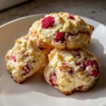 A stack of three freshly baked lemon raspberry cookies recipe treats on a white plate.