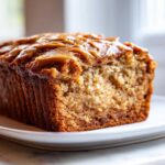 Close-up of a moist loaf of peanut butter banana bread topped with a thick peanut butter glaze.