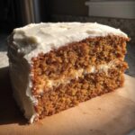 Close-up of a thick slice of moist spice cake layered with cream cheese frosting.