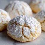 Close-up of a freshly baked zesty lemon meltaway cookie heavily dusted with powdered sugar.
